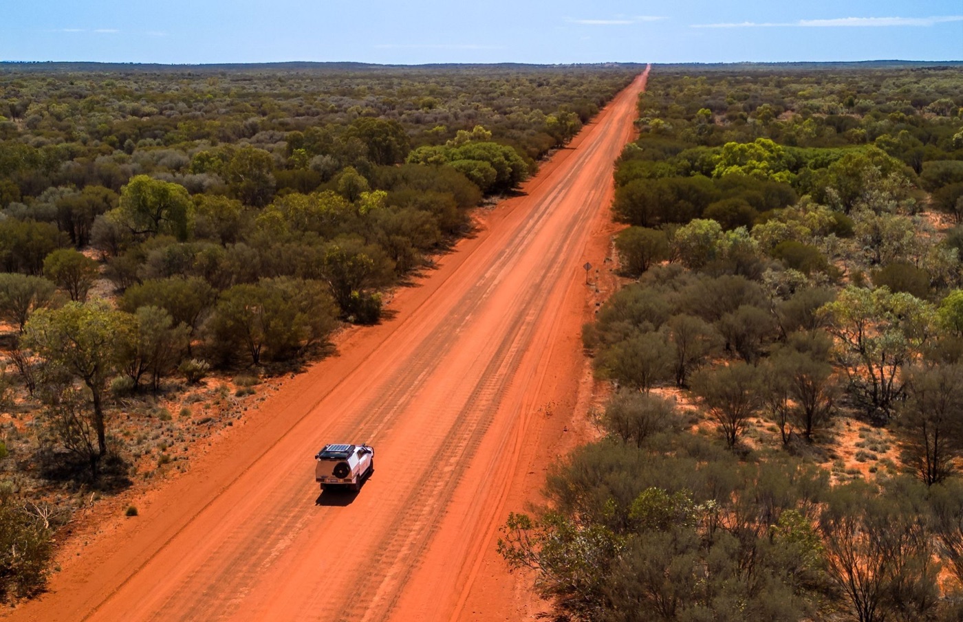 Veicolo 4x4 su una pista rossa del Red Centre, tra vegetazione bassa e orizzonte desertico